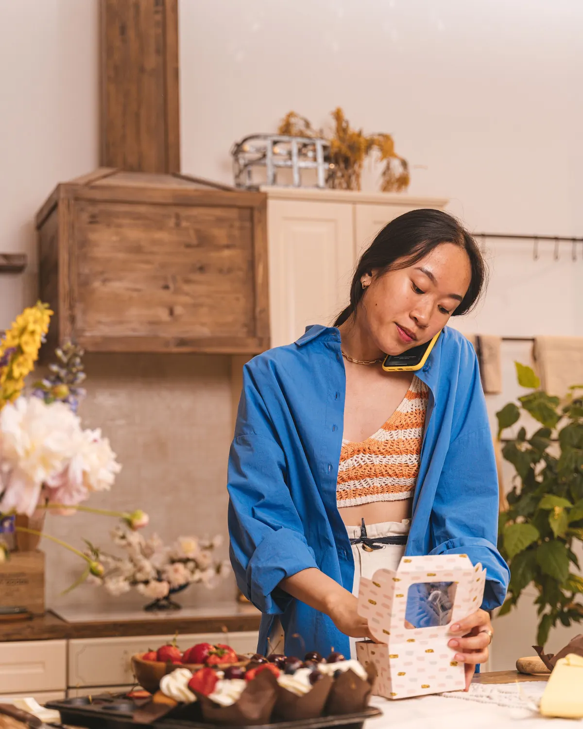 A bakery owner checking an order on her phone behind the counter